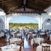 Ristorante ampio con tavoli apparecchiati e vista su giardino.