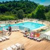 Piscina all'aperto con lettini, scivolo e vegetazione circostante.