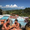 Coppia brinda con piscina e montagne sullo sfondo.