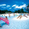 Una piscina affollata con persone che nuotano e si rilassano al sole.