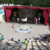 Un palco all'aperto con persone e pubblico seduto.