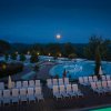 Piscina con lettini e luna piena nel cielo serale.