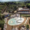 Vista aerea di un complesso turistico con piscine e vegetazione.