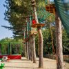 Percorso avventura tra gli alberi con corde e piattaforme.