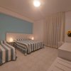 Camera da letto con tre letti a righe blu e bianche, tende lunghe e decorazione floreale.