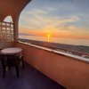 Balcone con due sedie e un tavolo, vista tramonto sul mare.