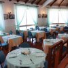 Una sala da pranzo con tavoli apparecchiati e sedie blu, tende azzurre alle finestre.