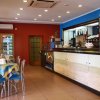 Interno di un bar con tavoli apparecchiati e un bancone lungo sulla destra.