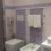 Bagno moderno con piastrelle viola, doccia, wc, bidet e lavabo doppio.
