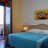 Camera da letto con letto matrimoniale, coperta blu, quadro di margherite e balcone aperto.
