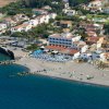 Veduta aerea di un complesso vicino al mare con spiaggia e ombrelloni distribuiti.