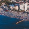 Spiaggia affollata con ombrelloni vicino a edifici.