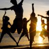 Persone saltano sulla spiaggia al tramonto.
