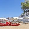 Spiaggia con ombrelloni bianchi e barca rossa da salvataggio.