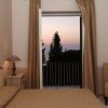 Stanza con letto, finestra aperta e vista tramonto.