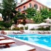 Piscina con lettini e ombrelloni davanti a un edificio.