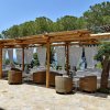 Area lounge all'aperto con divani, tende bianche e vista mare.