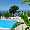 Vista piscina con mare e alberi sullo sfondo.