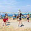 Persone giocano a beach volley vicino al mare.