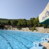 Piscina all'aperto con blocchi di partenza e ombrelloni.