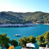 Una baia con acqua turchese e una barca, circondata da colline verdi.
