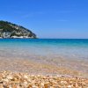Spiaggia con ciottoli e mare blu.