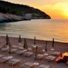 Spiaggia con lettini e mare al tramonto.