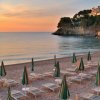 Spiaggia con ombrelloni chiusi al tramonto.