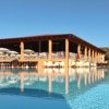 Piscina davanti a un edificio con sedie a sdraio e ombrelloni bianchi.