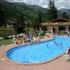 Piscina all'aperto con sdraio, montagne sullo sfondo.