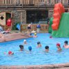 Piscina con scivolo gonfiabile e persone che nuotano.