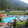 Piscina con scivolo gonfiabile e lettini intorno.