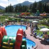 Piscina affollata con ombrelloni e gonfiabile verde.