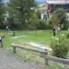 Campo da minigolf all'aperto con giocatori e alberi.