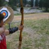 Un ragazzo tira con l'arco verso bersagli tondi su sfondo erboso.