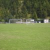 Ampio campo da calcio con porte multiple e alberi sullo sfondo.