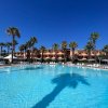 Piscina in un resort, con palme e edificio sullo sfondo sotto un cielo blu.