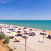 Spiaggia affollata con ombrelloni colorati.