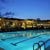 Piscina illuminata di sera con edificio sullo sfondo.