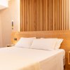 Camera elegante con letto e parete in legno verticale.