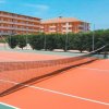 Campo da tennis arancione con edifici sullo sfondo.