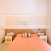 Letto singolo con copriletto arancione e comodini.
