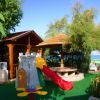 Parco giochi con uno scivolo rosso e una struttura a castello vicino a un gazebo in legno.