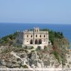 Edificio storico su una scogliera che si affaccia su un mare blu.