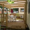 Veranda in legno con tavolo e sedie bianche.