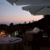 Tavolini all'aperto con candele e tramonto.