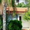 Casa con tetto rosso circondata da piante e palme.