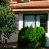 Una casa con tetto rosso circondata da piante verdi.
