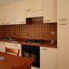 Cucina con mobili bianchi, lavello e fornelli.