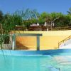 Piscina all'aperto con cascata, palme e cielo blu.